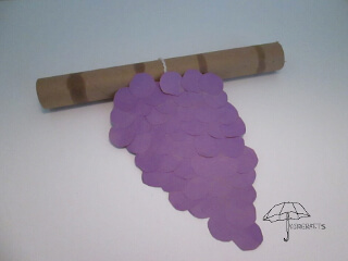 purple paper grape cluster tied to a cardboard roll grape cluster on a pole