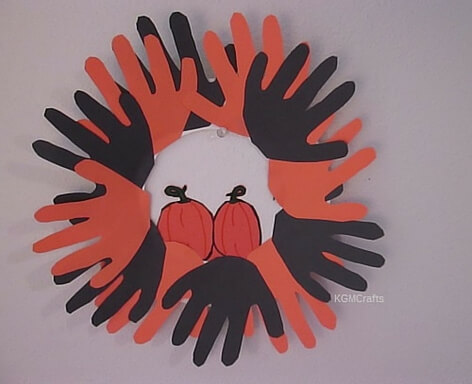 black and orange hand prints pumpkin in center fall wreath